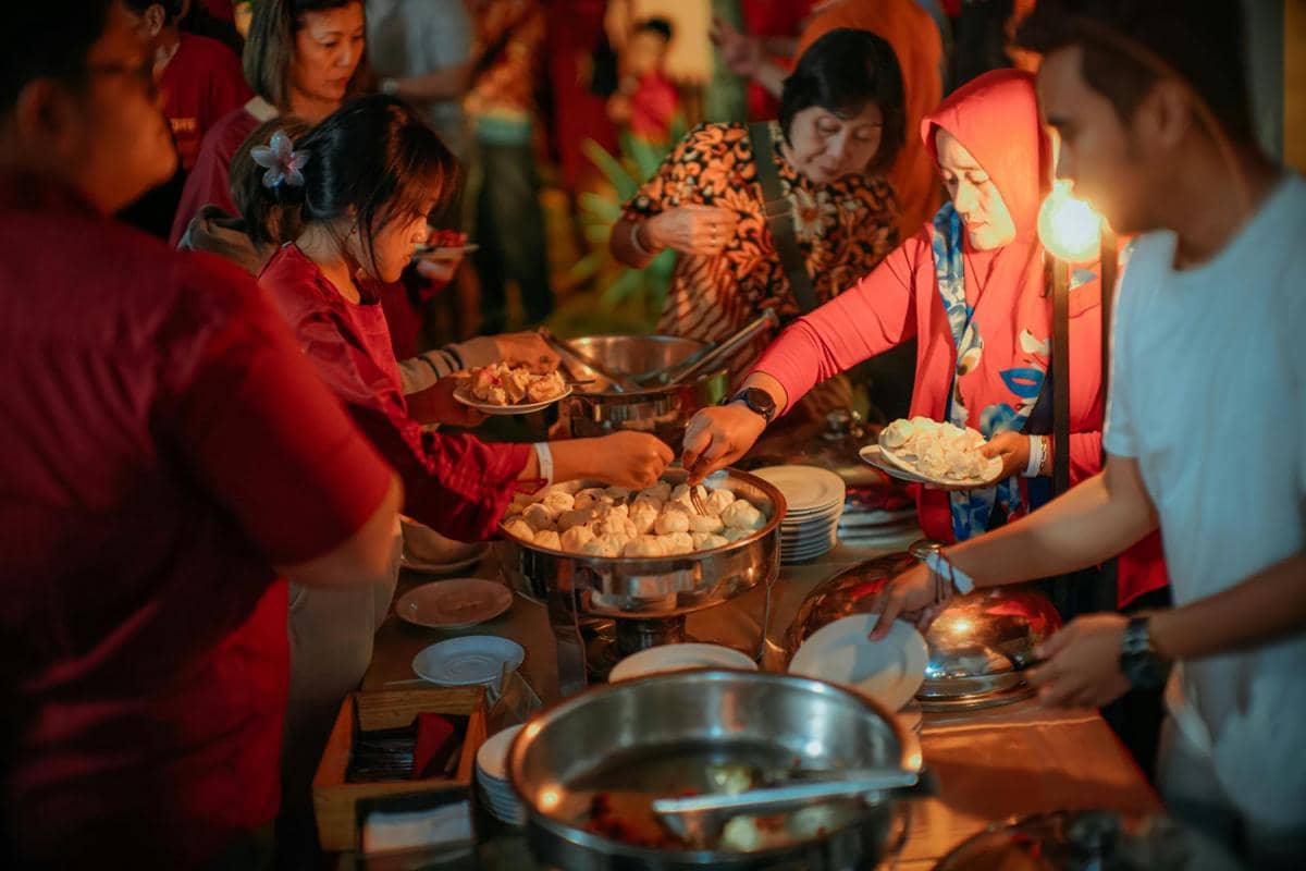 Beberapa orang mengambil makanan dari meja prasmanan dengan berbagai hidangan dalam wadah stainless steel pada acara catering.