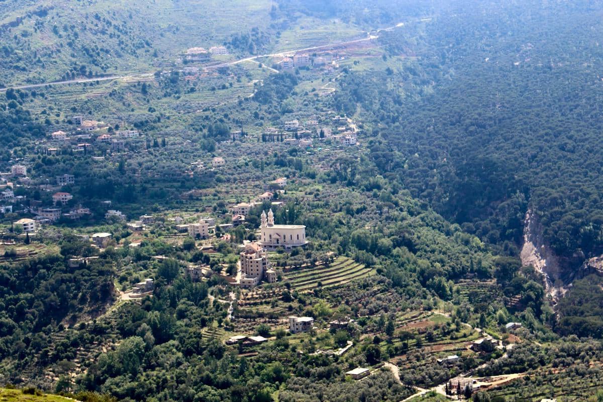 Pemandangan udara sebuah desa di Lebanon dengan rumah-rumah tersebar di antara perbukitan hijau dan ladang bertingkat yang subur.