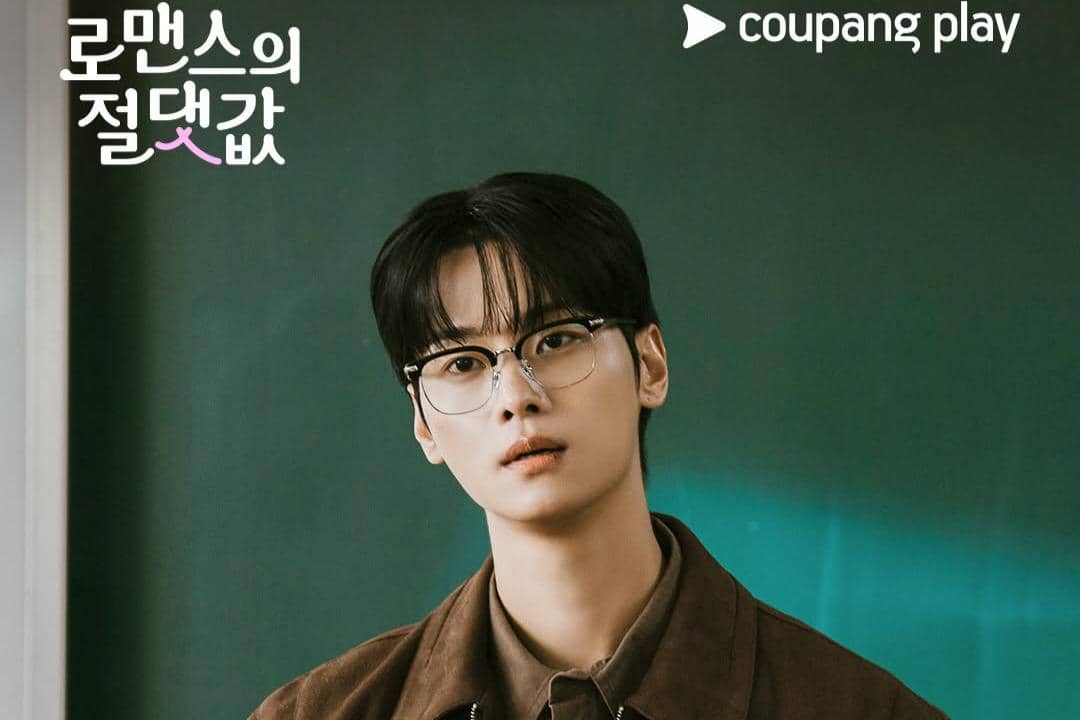 Seorang pria berambut hitam mengenakan kacamata dan jaket cokelat berdiri di depan papan tulis dengan logo Coupang Play di pojok kanan atas.