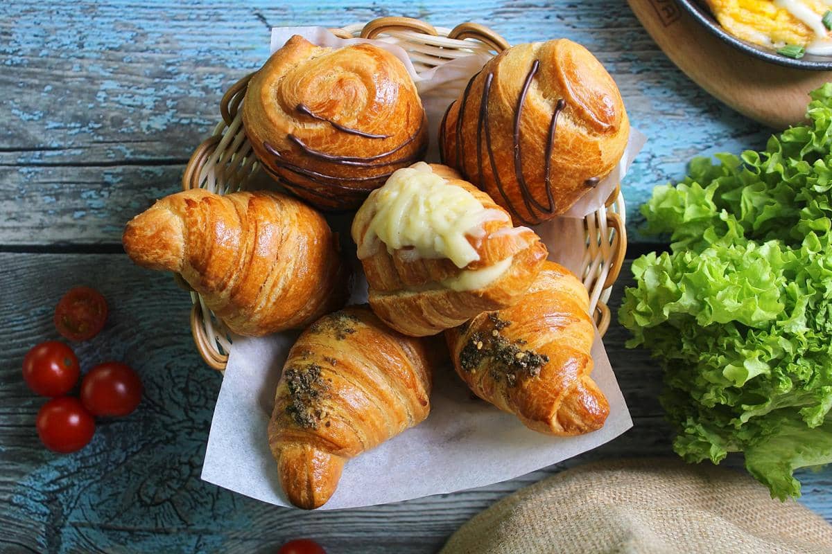 Ilustrasi croissant sourdough dengan tekstur flaky dan isian creamy.