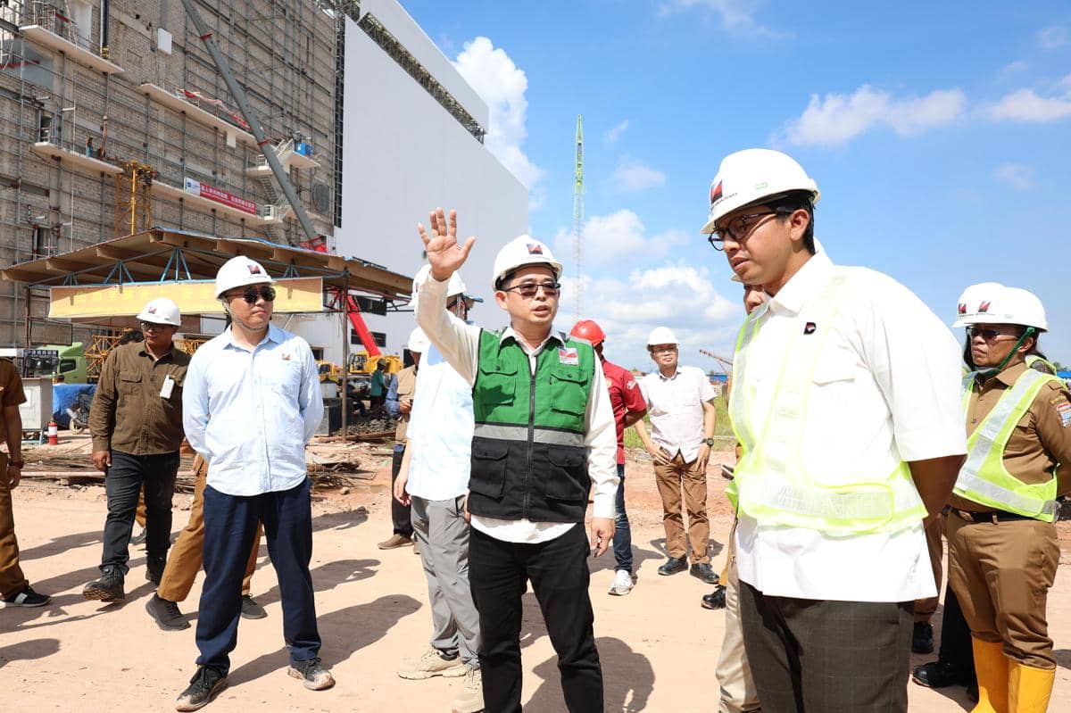 Sejumlah pejabat dan pekerja mengenakan helm proyek saat meninjau area pembangunan PSEL Keramasan di Palembang di bawah langit cerah.