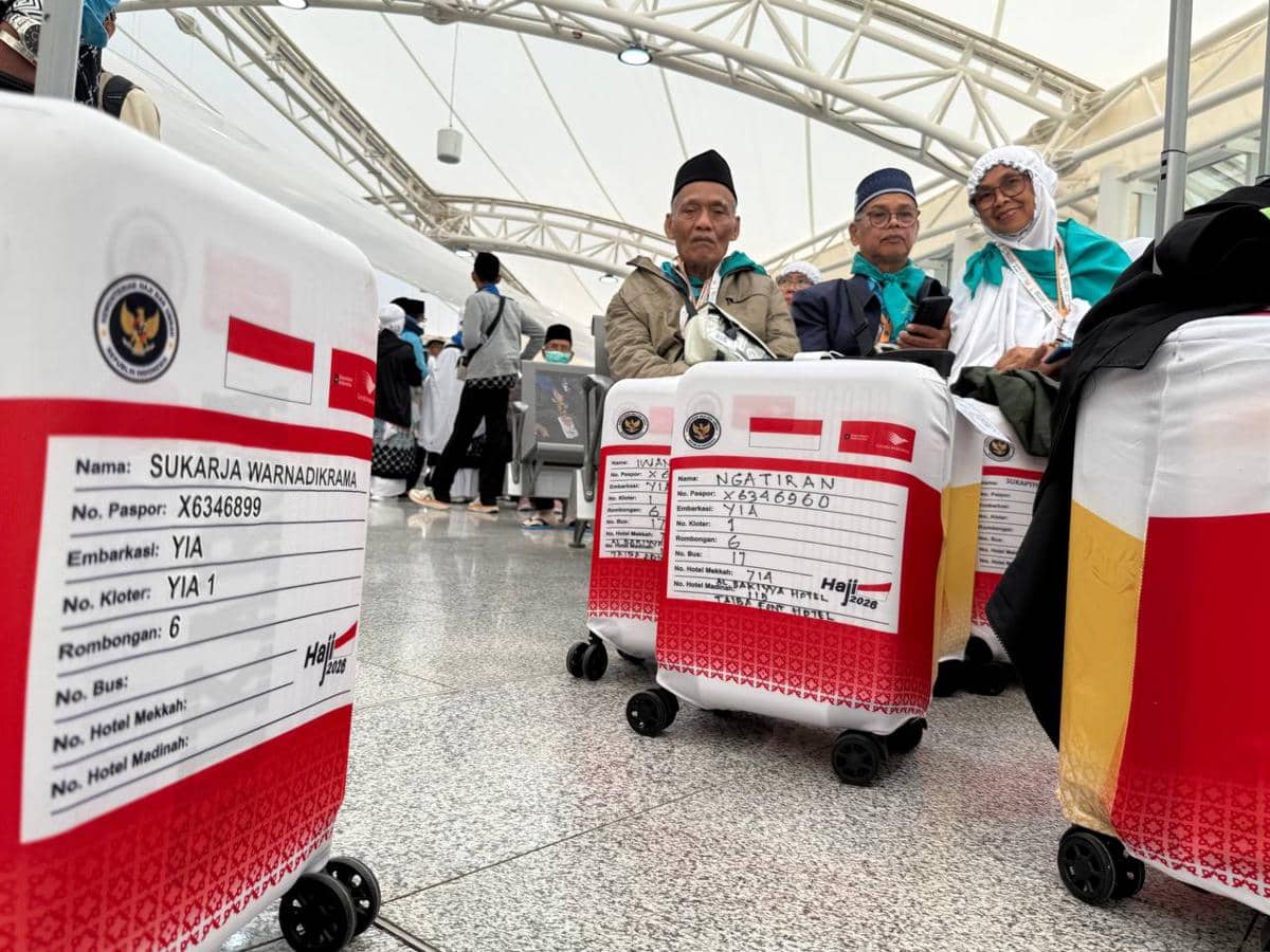Jemaah haji asal embarkasi YIA 1 duduk bersama koper berlabel merah putih di Bandara Internasional Prince Mohammed bin Abdul Aziz.
