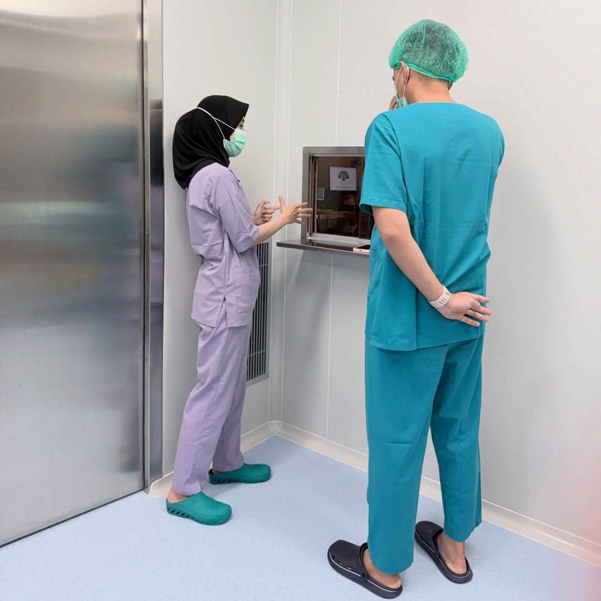 tenaga medis dan Rezky Aditya mengenakan pakaian bedah dan masker berdiskusi di ruang laboratorium rumah sakit selama proses bayi tabung.