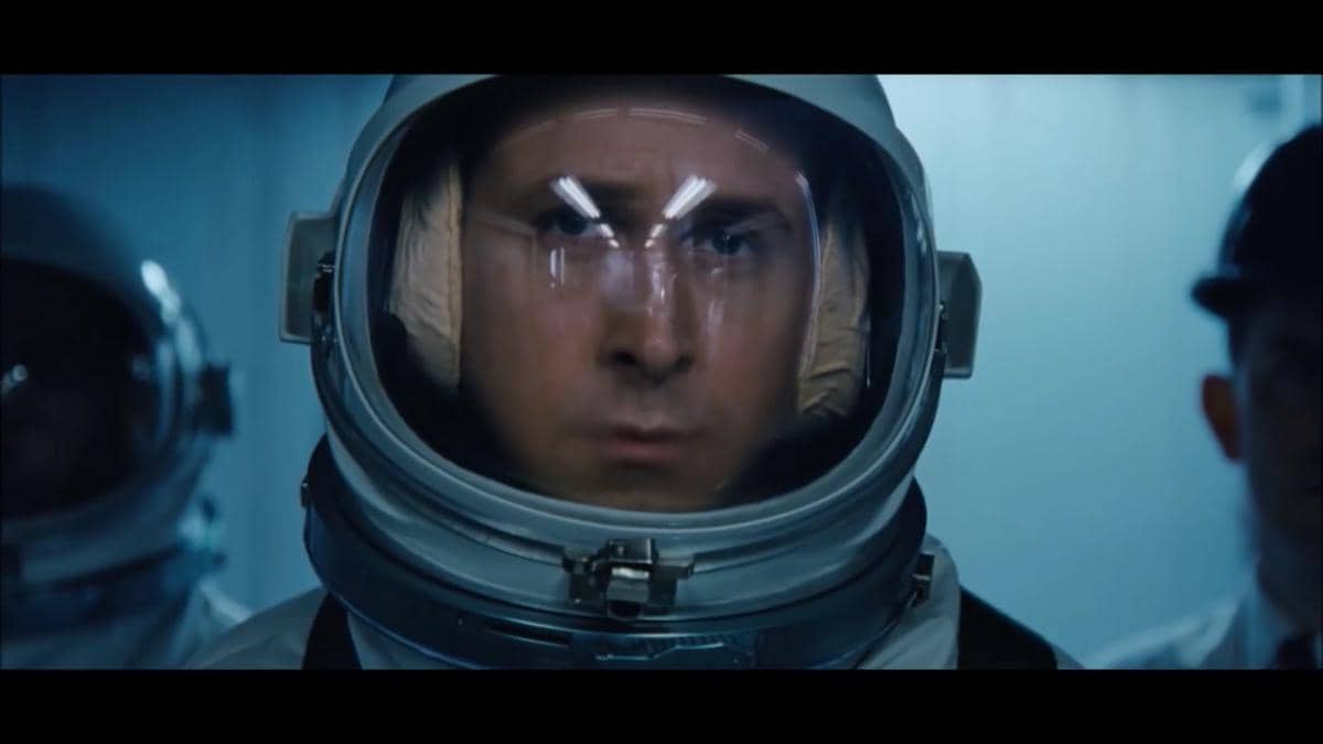 Seorang astronot mengenakan helm luar angkasa dengan ekspresi serius di dalam ruangan berwarna biru dalam adegan film First Man.