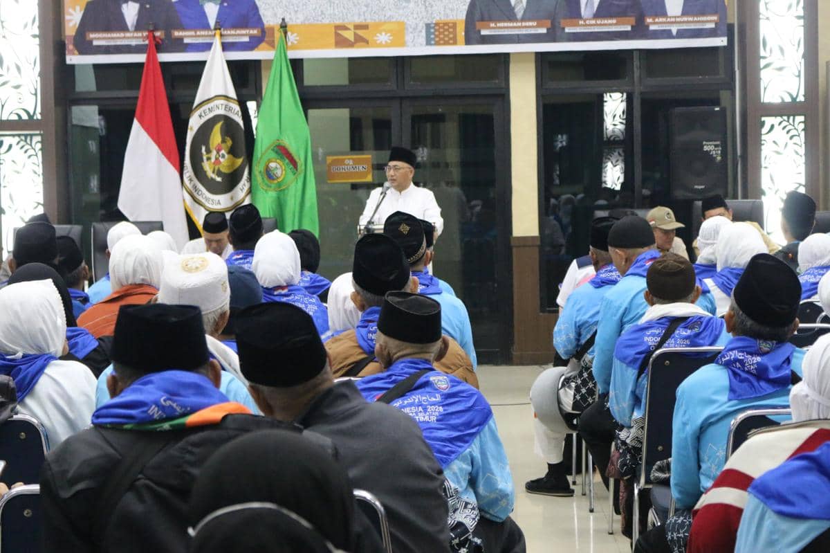 Sambutan PPIH di depan jemaah haji yang mengenakan pakaian biru dan sorban putih di asrama haji