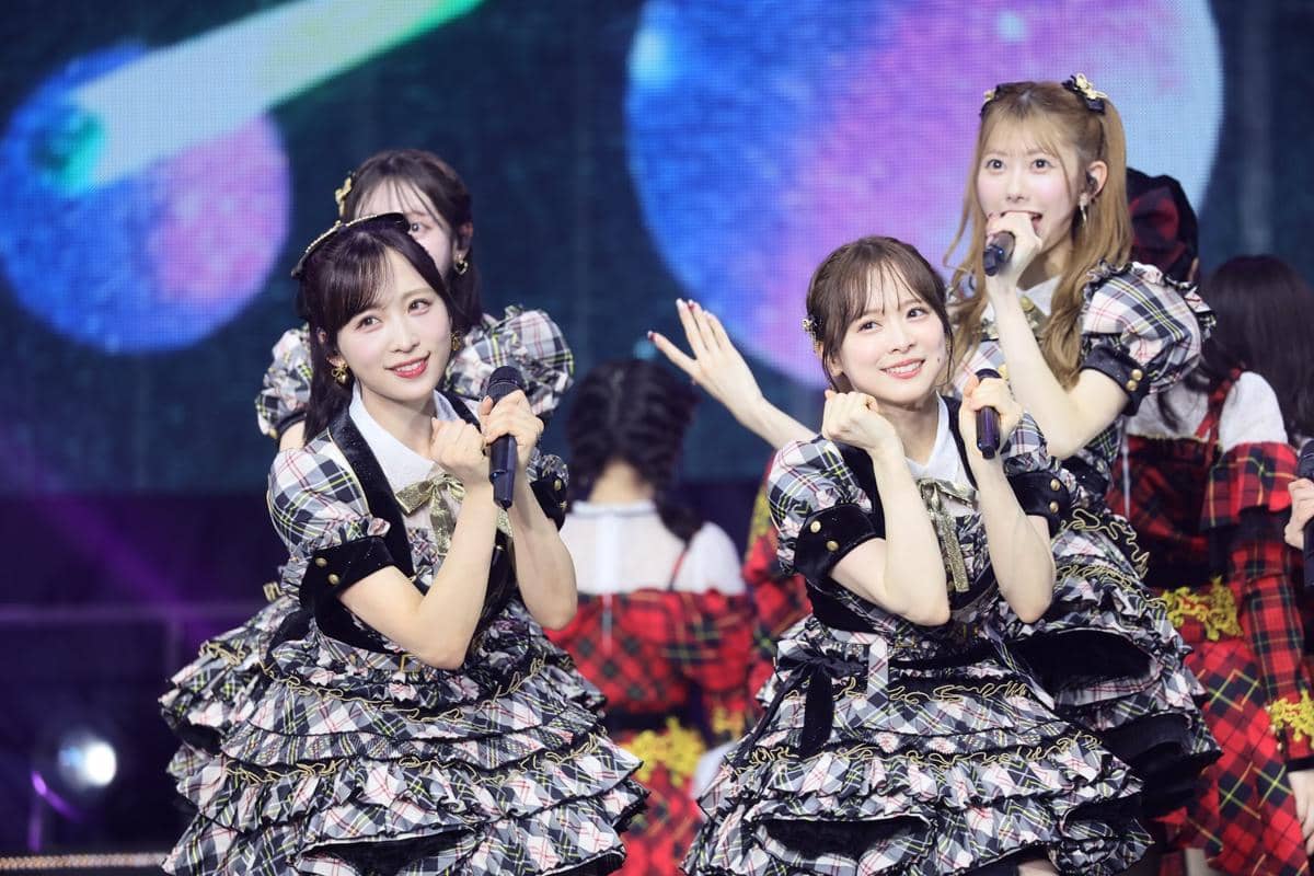Para anggota grup idola Jepang AKB48 tampil di atas panggung dengan kostum bermotif kotak-kotak dan pencahayaan warna-warni.