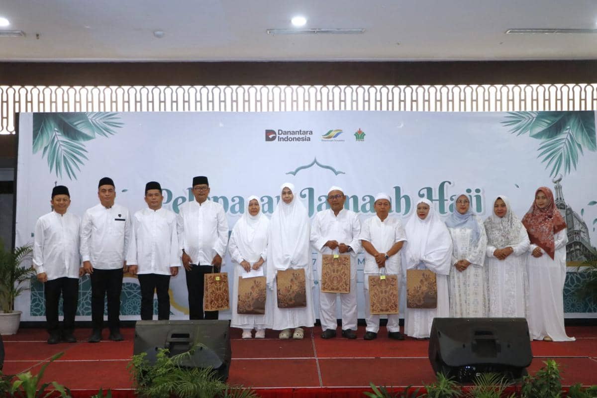 Sejumlah pegawai PTPN IV Regional II berfoto bersama dalam acara pelepasan jemaah haji, mengenakan busana putih di atas panggung.