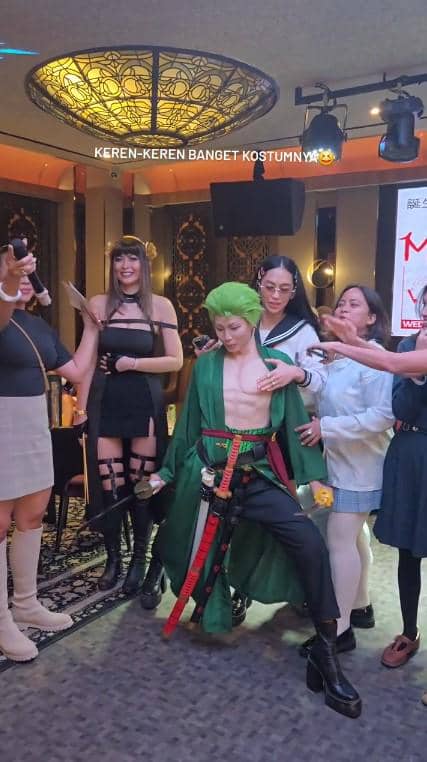Beberapa orang mengenakan kostum cosplay anime di pesta ulang tahun bertema di sebuah ruangan dengan pencahayaan hangat.
