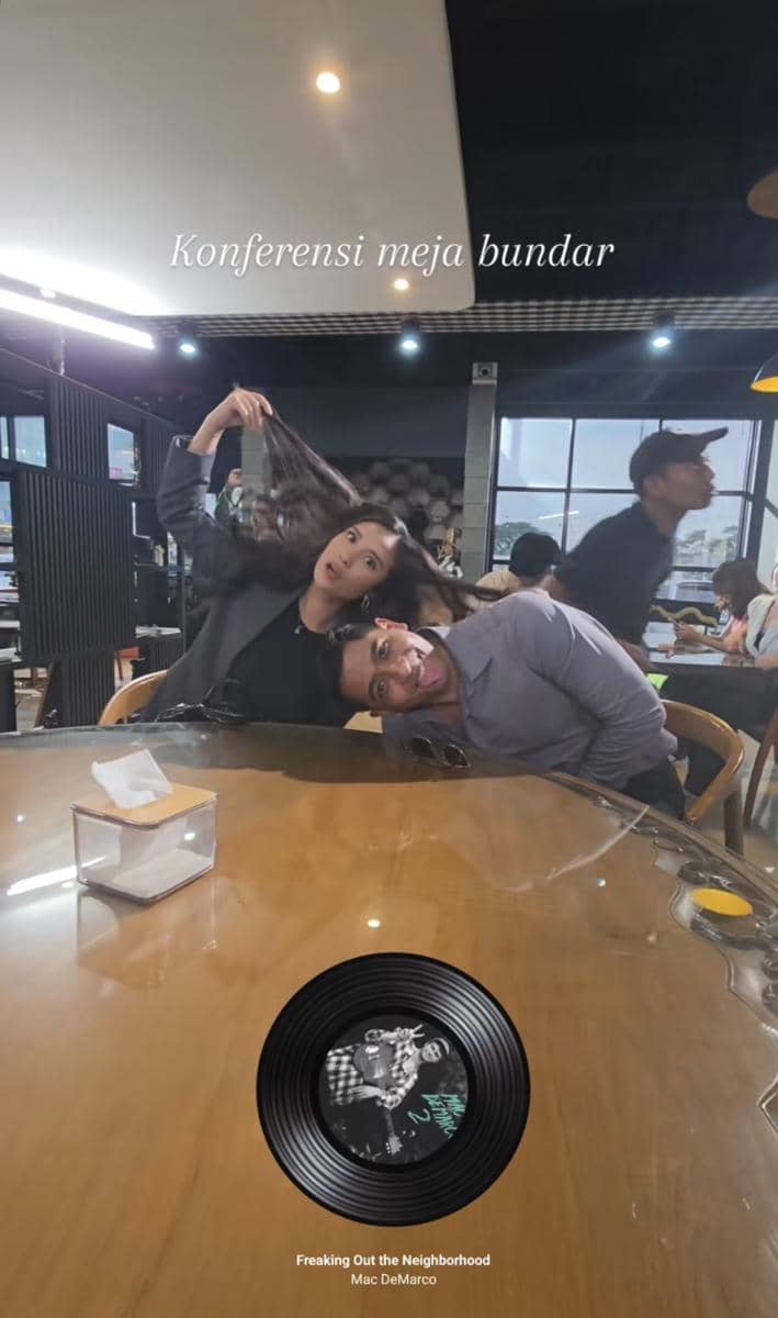 Dua orang berpose lucu di meja bundar di lokasi syuting sinetron Terikat Janji dengan suasana santai di dalam ruangan.