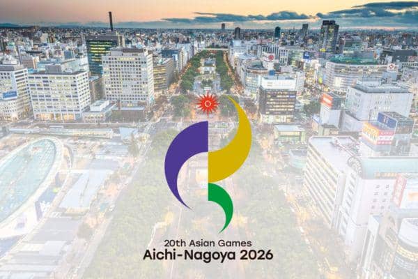Logo Asian Games 2026 Aichi-Nagoya dengan latar belakang kota modern yang dipenuhi gedung tinggi dan jalan utama yang ramai.