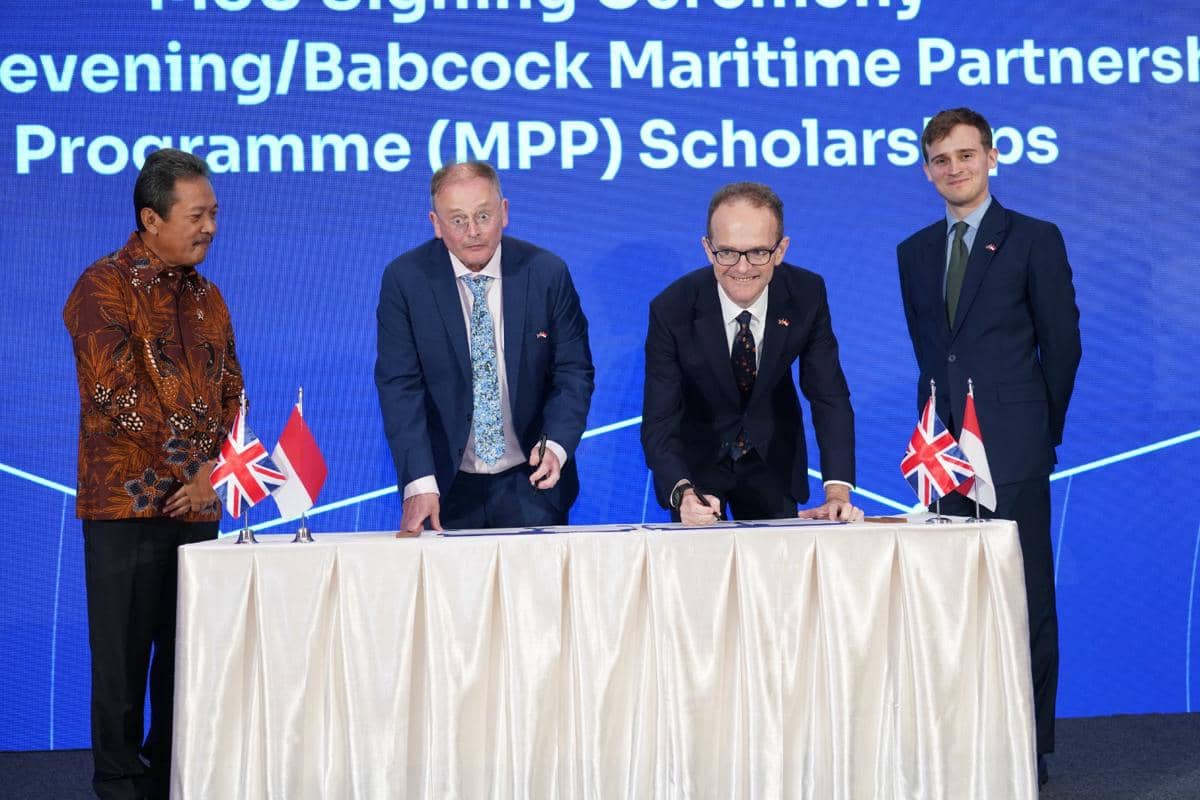 Perwakilan Indonesia dan Inggris menandatangani kerja sama kemaritiman di atas meja dengan bendera kedua negara di depannya.