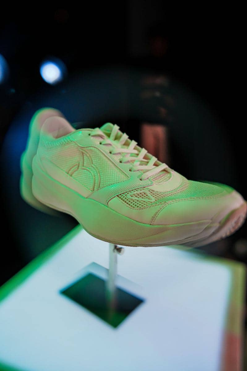 Sepatu olahraga baru Ortuseight berwarna terang dipajang di atas dudukan dengan pencahayaan hijau dalam peluncuran tahun 2026.