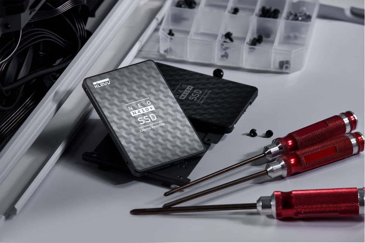 SSD Klevv Neo N410+ berwarna hitam dengan pola geometris diletakkan di meja bersama obeng merah dan sekrup kecil.
