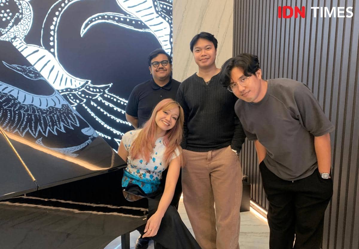 Empat anggota band Reality Club berpose di dekat piano hitam di kantor IDN dengan latar mural bergambar burung berwarna putih.