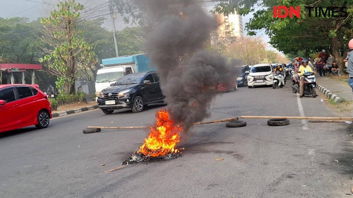 Kendaraan terjebak macet di Jalan Urip Sumoharjo Makassar dengan api dan asap hitam di tengah jalan akibat aksi blokade mahasiswa.