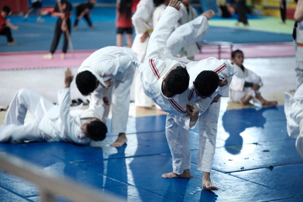 Peserta pelatihan CASN Lapas Tabanan berlatih teknik bela diri judo di atas matras biru dengan mengenakan seragam putih.