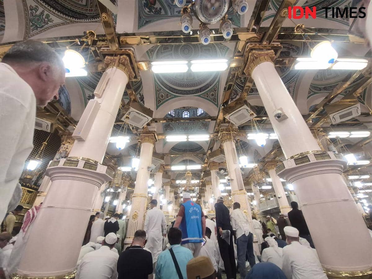 Jemaah berpakaian putih memenuhi area Raudhah dengan pilar berornamen emas dan lampu gantung megah di Masjid Nabawi.