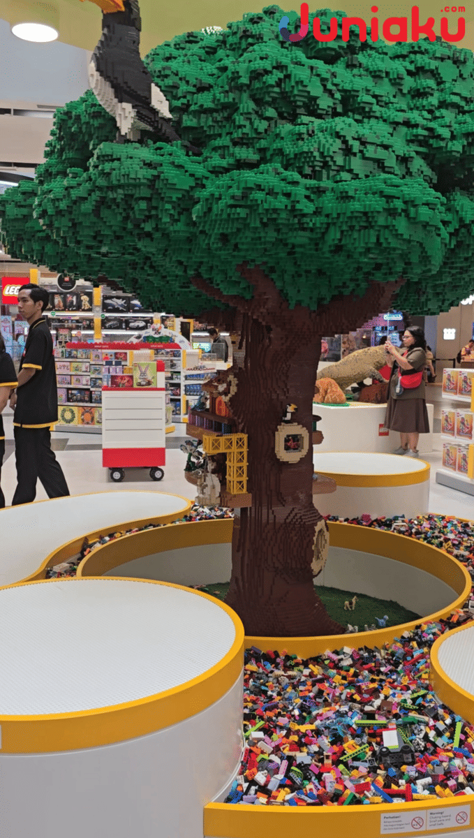 Instalasi pohon besar dari LEGO dengan detail rumah pohon dan burung di LEGO Certified Store Grand Indonesia, dikelilingi area bermain balok LEGO.
