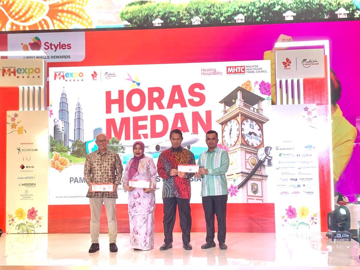 Empat perwakilan berdiri di panggung acara Malaysia Healthcare Expo 2026 di Sun Plaza Medan dengan latar bertuliskan Horas Medan.