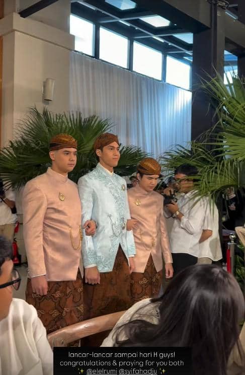 Tiga pria mengenakan busana adat Jawa berwarna pastel dengan blangkon, berdiri berdampingan di acara pengajian dan siraman.