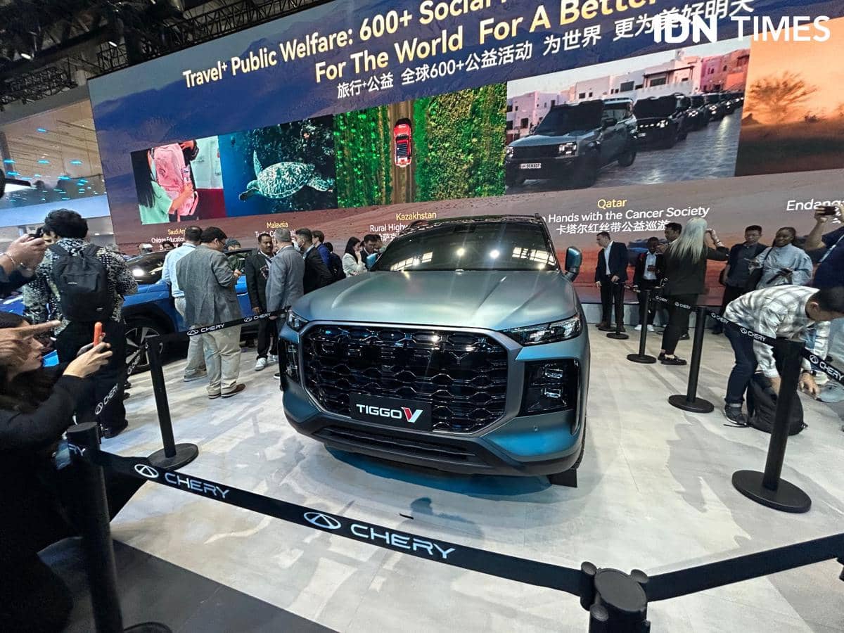 Mobil Chery Tiggo V berwarna abu-abu dipamerkan di sebuah acara otomotif dengan banyak pengunjung yang melihat dan memotret.