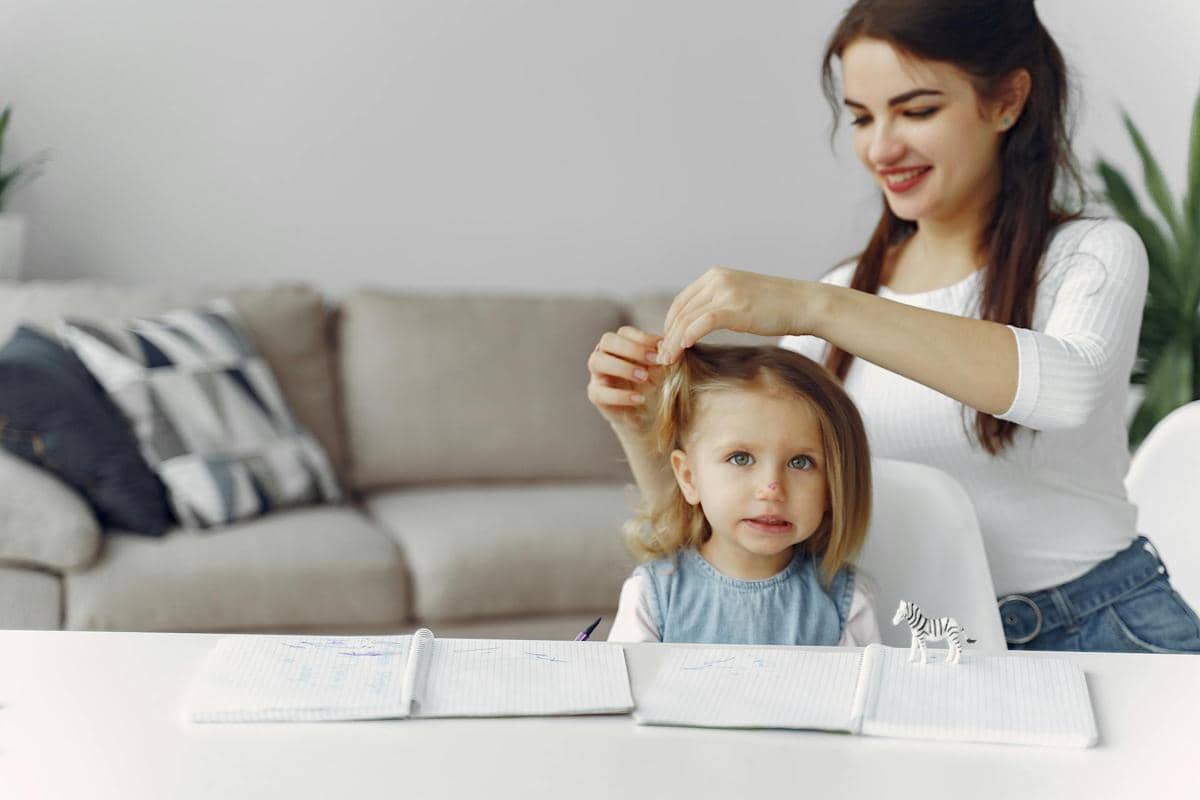 pekerja rumah tangga mengikat rambut anak kecil