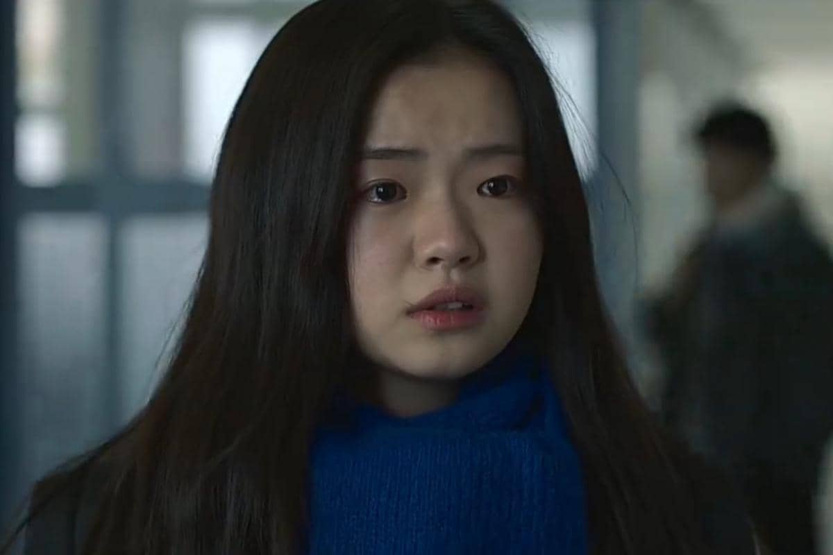 Seorang gadis berambut panjang mengenakan syal biru tampak cemas di sebuah koridor dalam adegan serial If Wishes Could Kill.