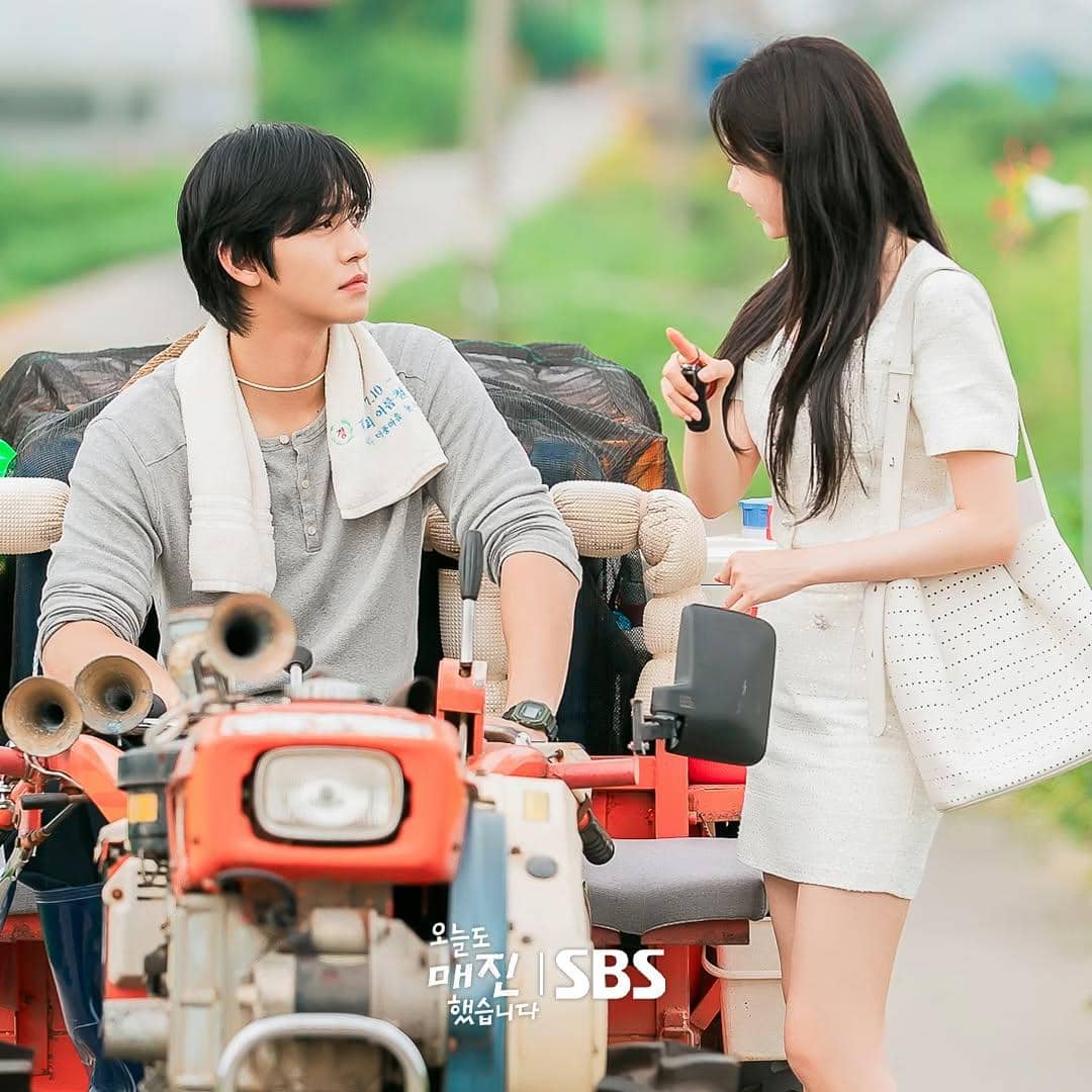 Dua karakter dalam drama Sold Out On You berbincang di luar ruangan, pria duduk di traktor sementara wanita berdiri di sampingnya.