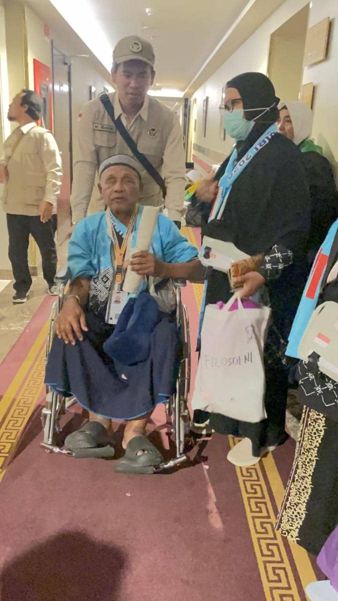 Jamaah haji lansia duduk di kursi roda didampingi keluarga dan petugas PPIH di lorong hotel sebelum berangkat menuju Masjid Nabawi.