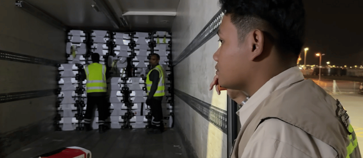 Petugas Haji mengawasi proses pemindahan bagasi jamaah ke dalam truk pada malam hari dengan pengawasan ketat di area kargo.