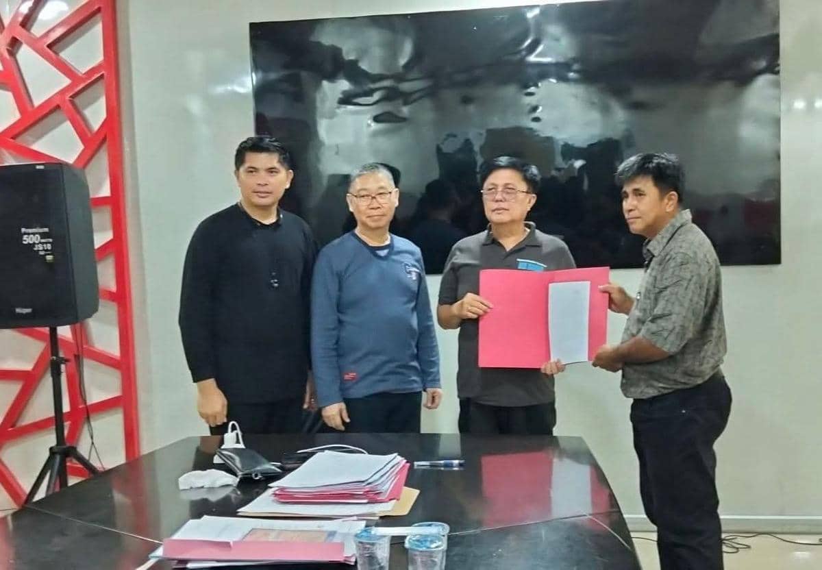 Empat pria berpose di ruang pertemuan saat penyerahan SK Plt Lurah Airmadidi Atas oleh Pemkab Minut, dengan dokumen berwarna merah muda.