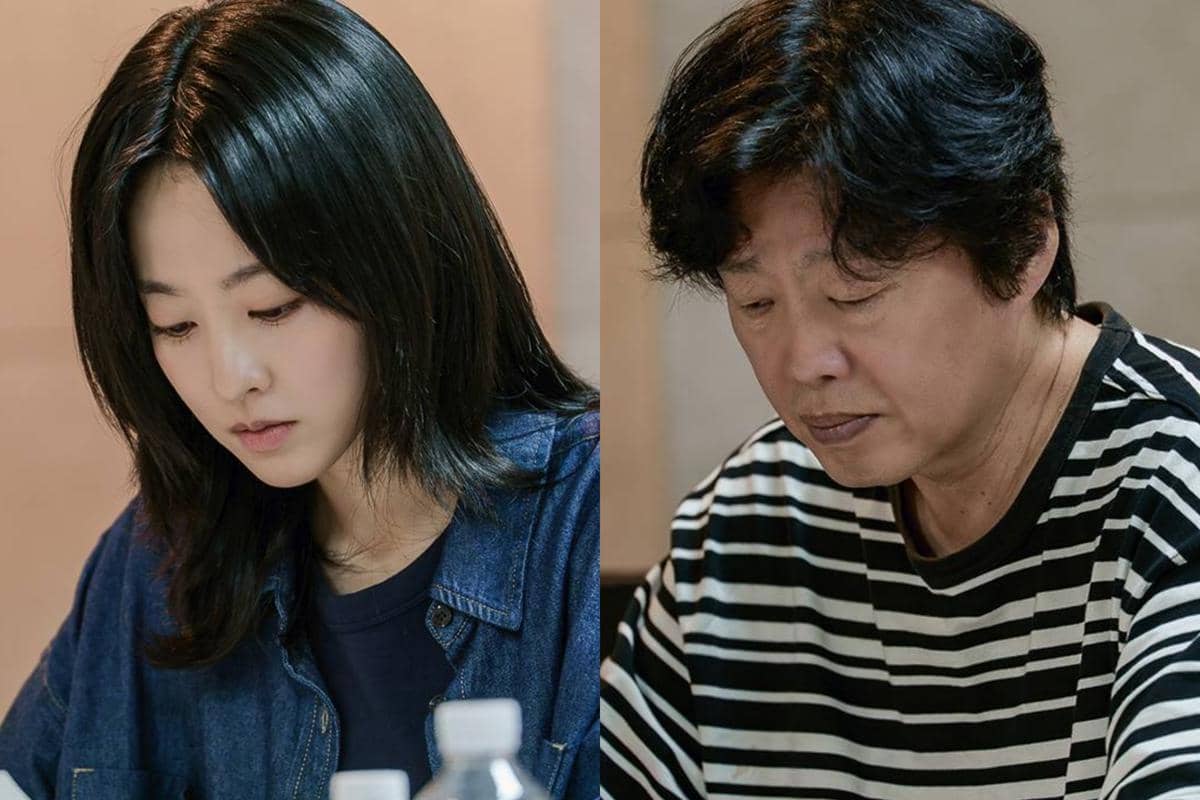 Dua orang duduk berdampingan dengan ekspresi serius, masing-masing mengenakan pakaian kasual dan tampak fokus pada sesuatu di depan mereka.