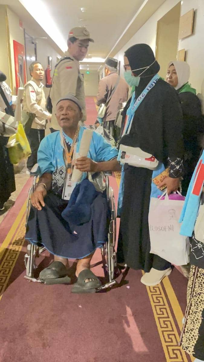 Seorang jamaah lansia duduk di kursi roda di lorong hotel, didampingi keluarga dan petugas PPIH sebelum berangkat ke Masjid Nabawi.