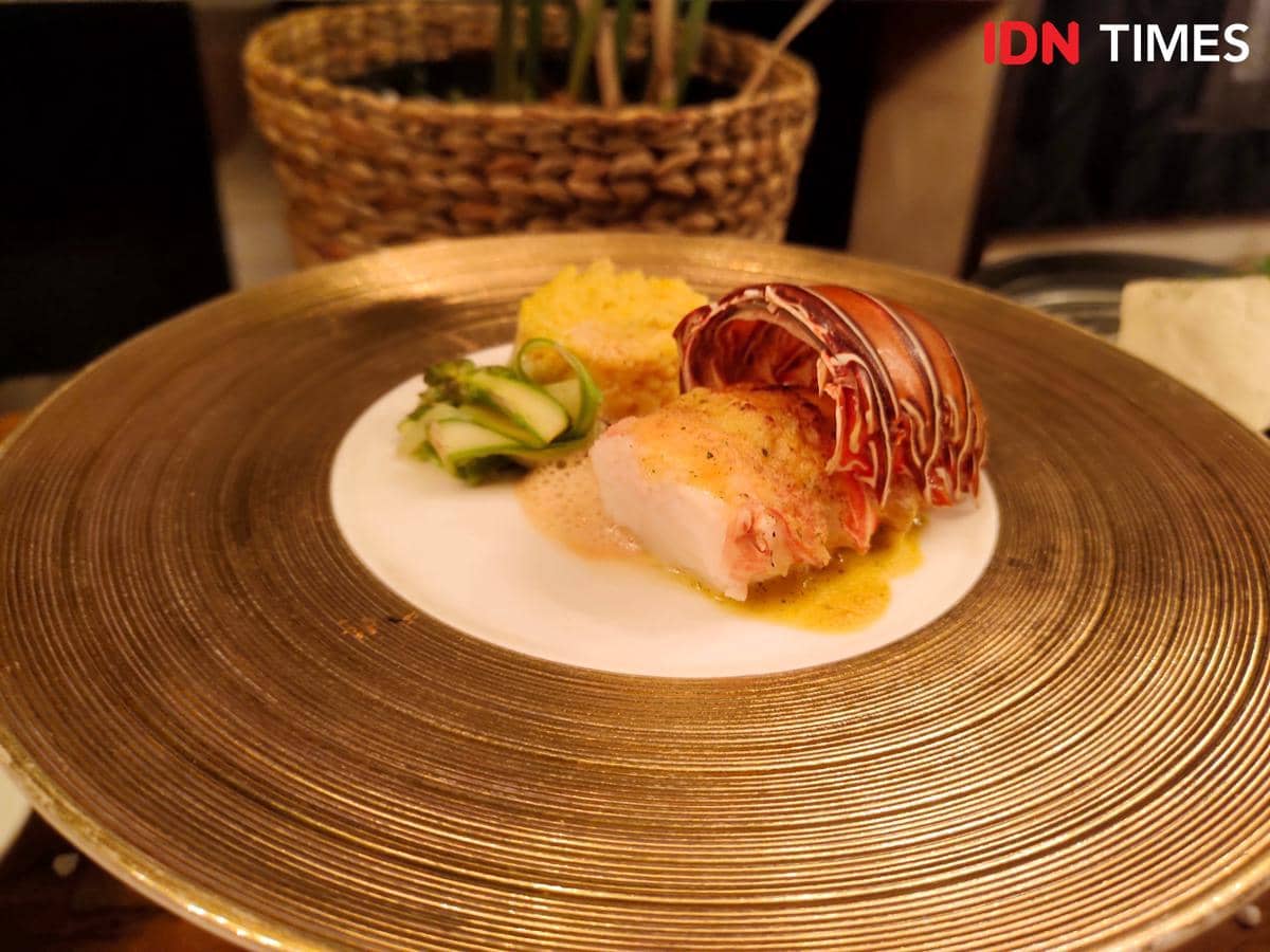 Hidangan laut mewah dengan potongan lobster dan saus kuning disajikan di piring berwarna emas di JW Marriott Hotel Medan.