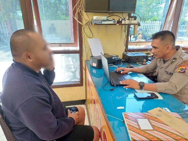 Seorang petugas polisi di Kupang sedang memeriksa dan mencatat keterangan seorang pria yang diduga terlibat pencurian helm di kantor polisi.