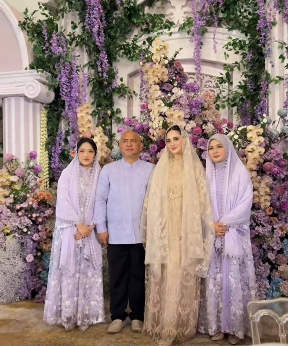 Empat orang berpose di depan dekorasi bunga ungu dan krem pada acara pengajian dan siraman, mengenakan busana tradisional bernuansa pastel.