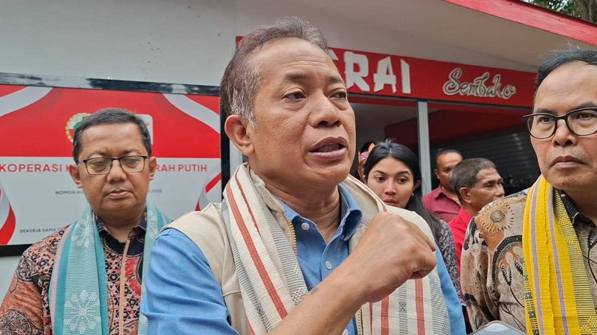 Seorang pejabat berbicara di depan umum saat kunjungan kerja di Kupang, didampingi beberapa orang dengan latar gedung koperasi.