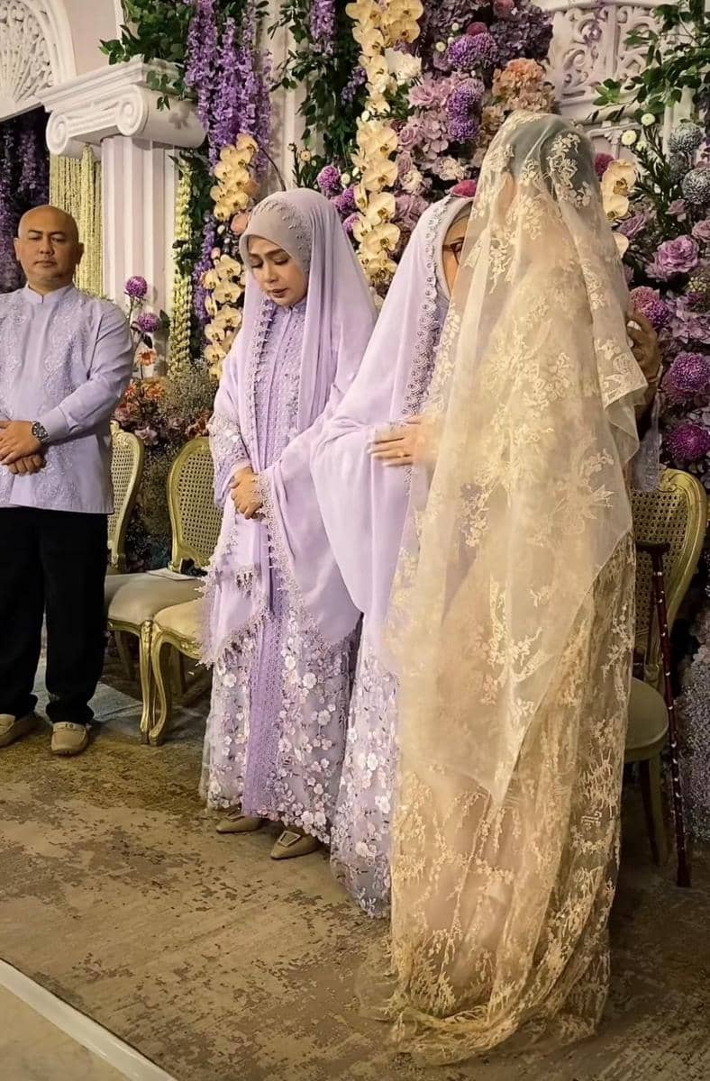 Beberapa orang mengenakan busana tradisional berwarna ungu dan krem dalam acara pengajian dan siraman dengan dekorasi bunga ungu dan putih.