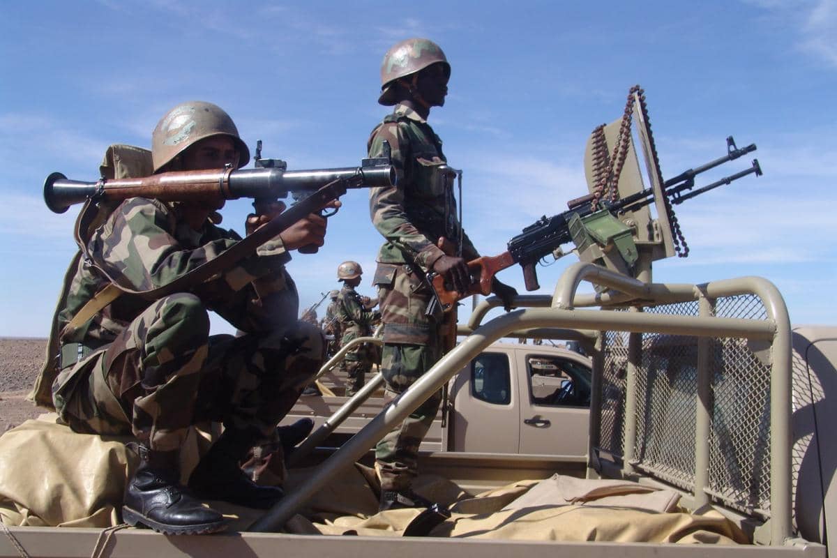 Prajurit Mali berseragam kamuflase bersiaga di atas kendaraan militer dengan senjata berat di area gurun terbuka di bawah langit cerah.
