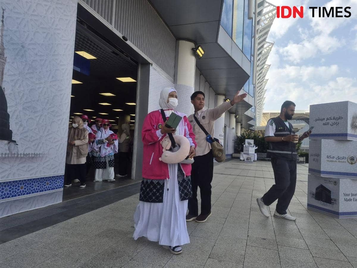 Rombongan jemaah haji asal Kota Malang mengenakan pakaian ihram dan jaket pink tiba di Madinah, dipandu petugas di area kedatangan.
