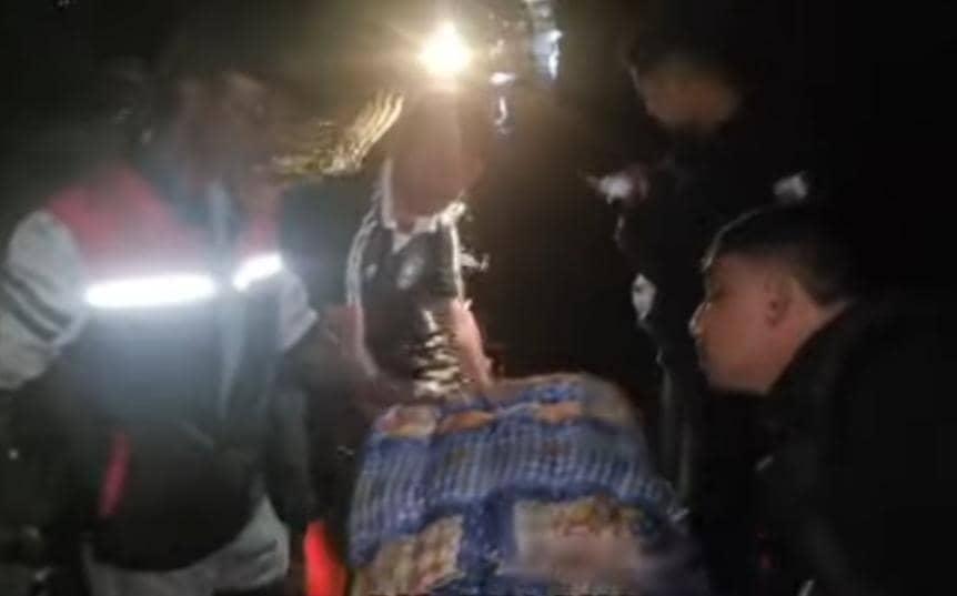 Beberapa orang dan polisi bekerja sama memindahkan peti jenazah dari ambulans ke mobil patroli di tengah banjir malam hari di Malaka.