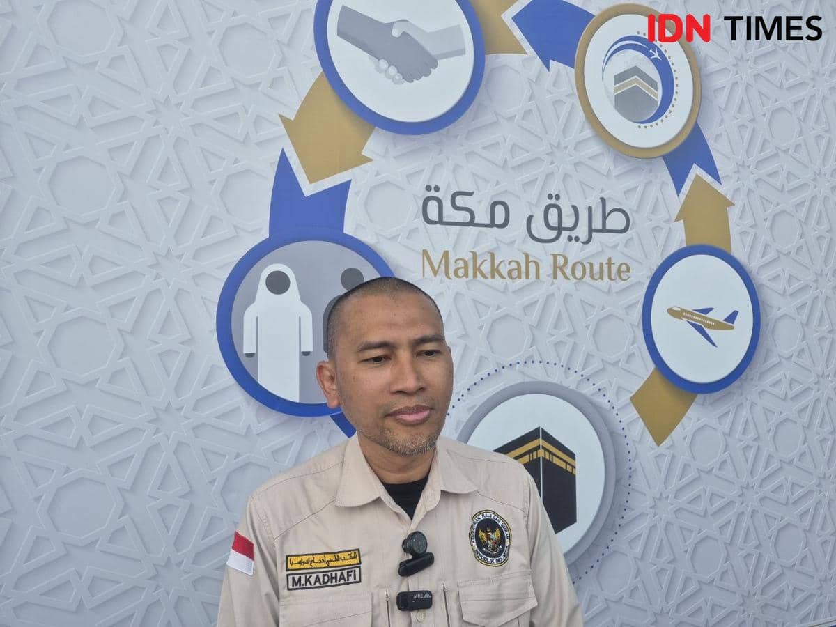 Petugas kesehatan Daker Bandara PPIH Arab Saudi mengenakan seragam krem dengan latar belakang logo Makkah Route bergambar ikon perjalanan haji.