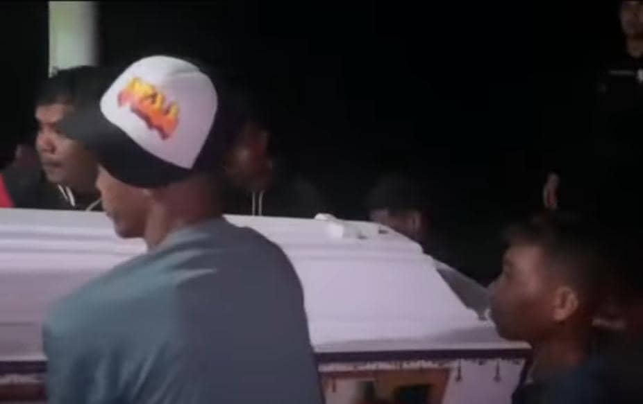 Beberapa orang bersama polisi mengangkat peti jenazah dari ambulans ke mobil patroli di tengah situasi banjir malam hari di Malaka.