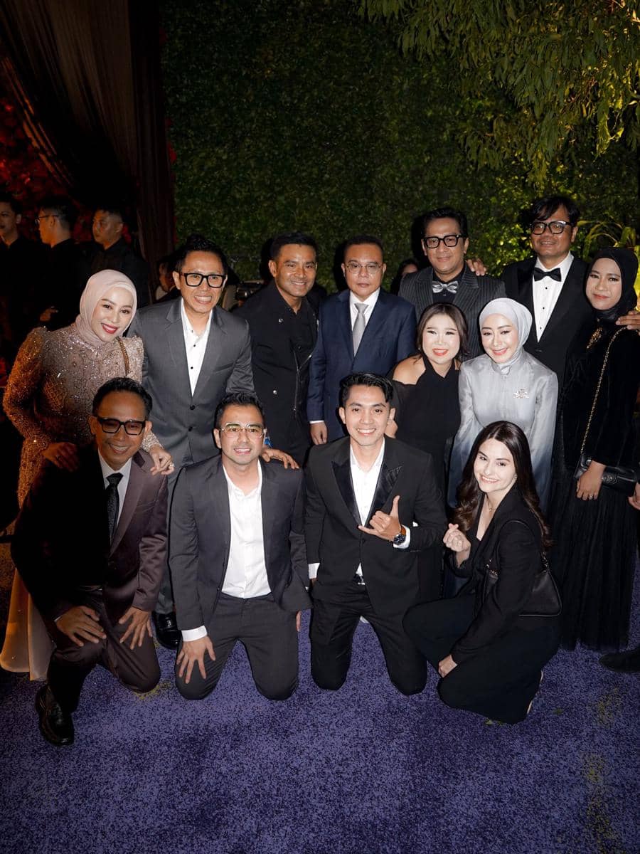 Sekelompok tamu berpakaian formal berpose bersama di resepsi pernikahan El Rumi dan Syifa Hadju dengan latar taman malam hari.