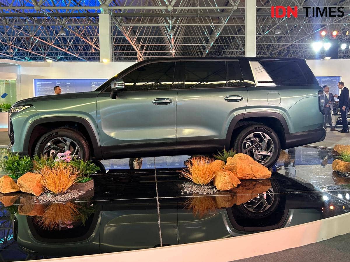 Mobil SUV Chery Tiggo V berwarna hijau metalik tampak dari sisi samping dipamerkan di sebuah acara otomotif dalam ruangan.