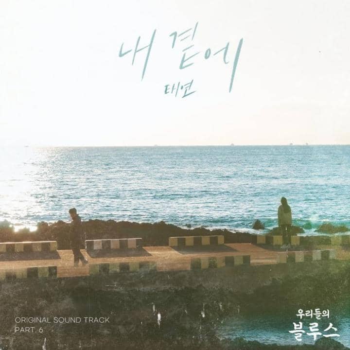Poster lagu 'By My Side' dari Taeyeon untuk OST drama Korea Our Blues menampilkan pemandangan laut dengan dua orang di tepi jalan.