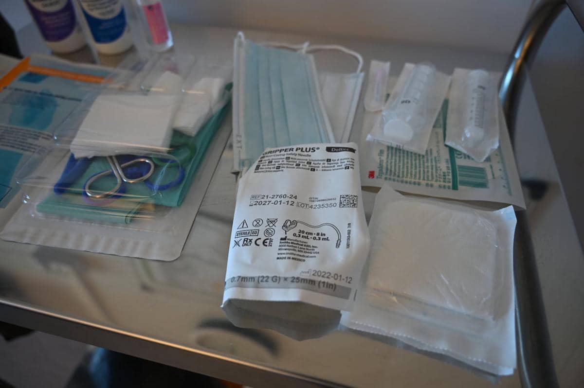 Peralatan medis steril seperti masker, gunting bedah, perban, dan jarum suntik tersusun di atas meja logam di ruang perawatan.