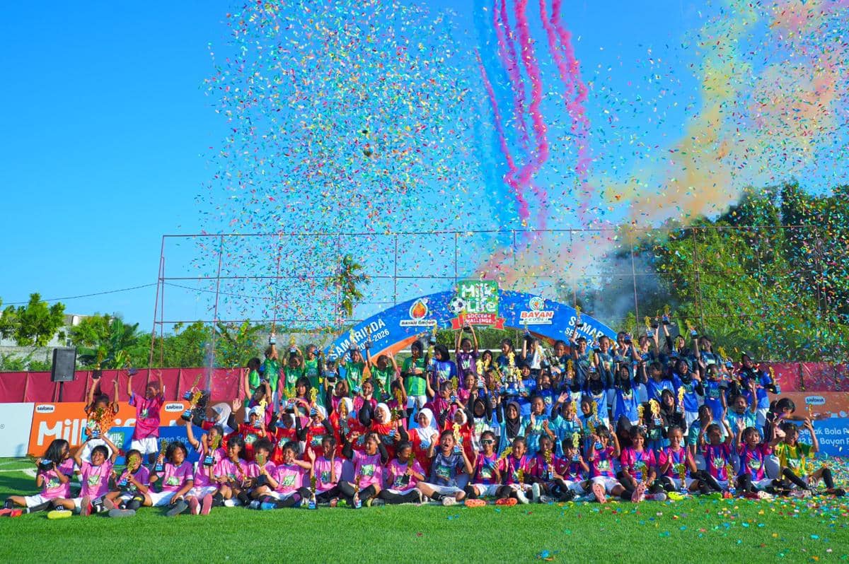 Peserta muda berpose bersama piala di lapangan hijau saat penutupan MLSC Samarinda Seri 2 2025-2026 dengan confetti berwarna-warni di udara.