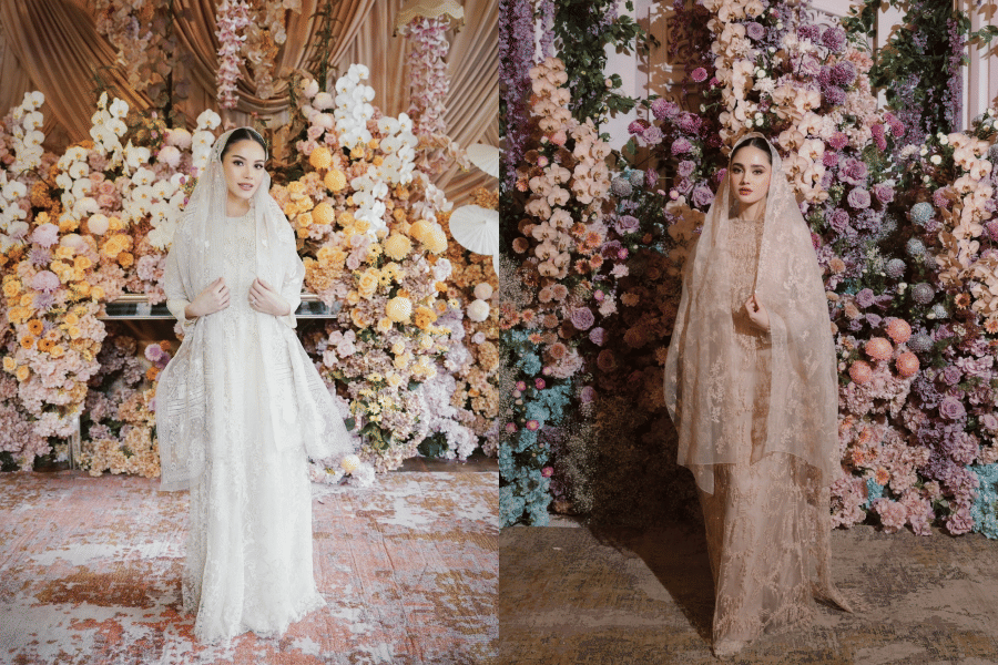Dua perempuan mengenakan busana pengantin berhijab dengan latar dekorasi bunga berwarna pastel yang elegan dan mewah.