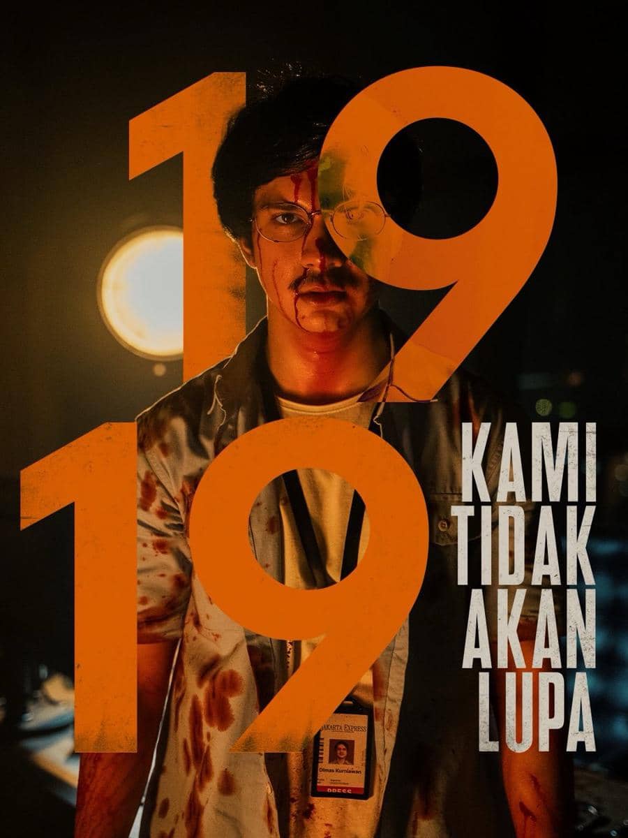 Seorang pria berlumuran darah berdiri di bawah cahaya redup dengan angka besar 1919 dan tulisan 'Kami Tidak Akan Lupa' di latar belakang.